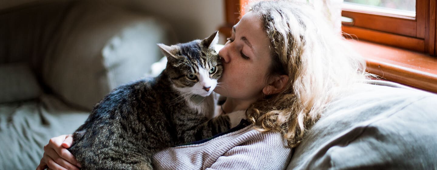 Donna che bacia gatto sulla guancia