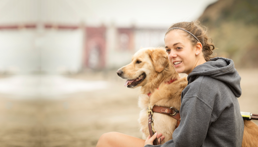 Donna seduta fuori con il suo cane al guinzaglio di fianco a lei