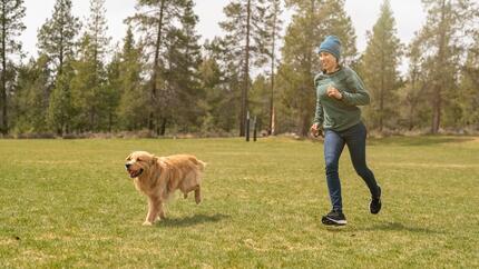 Un cane che corre in un campo insieme a un uomo