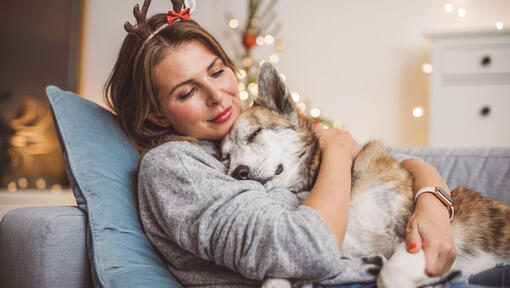 donna che indossa le corna che abbraccia il suo cane addormentato