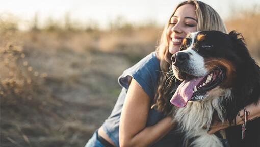 Una ragazza felice che abbraccia il suo cane.